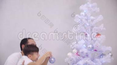 小儿子想把粉红色的宝布尔挂在树的顶枝上，所以爸爸把他抱起来，孩子做他想做的事，然后做他想做的事